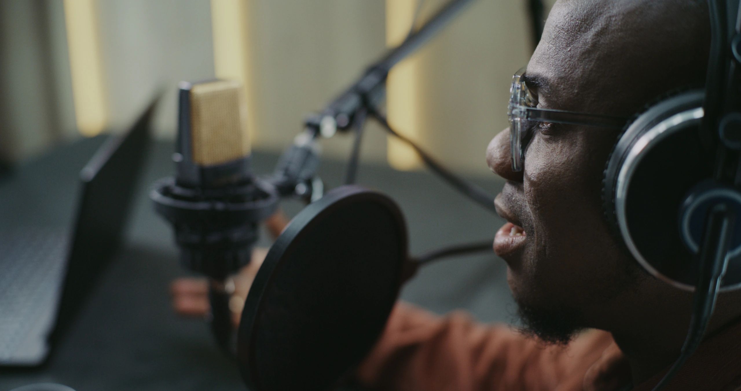 Radio host wearing headphones speaking into a microphone