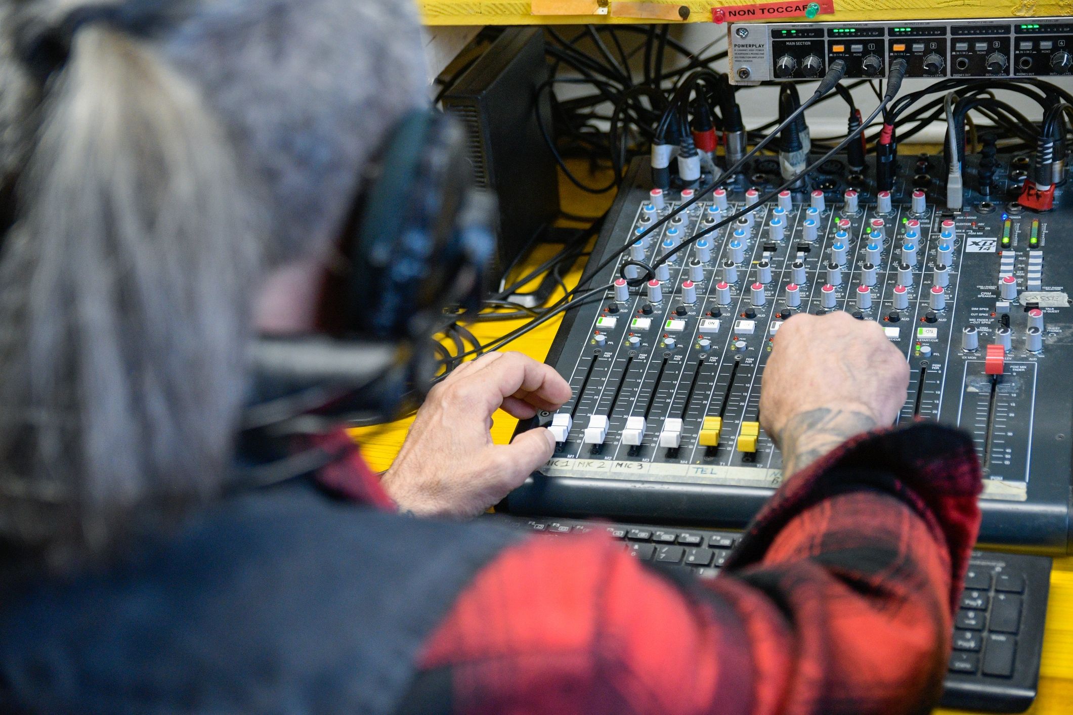 Radio DJ adjusting faders on a mixing console during a live broadcast